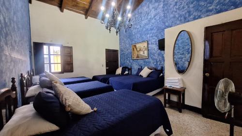 a bedroom with blue walls with beds and a mirror at Hotel Posada San Miguel in Antigua Guatemala