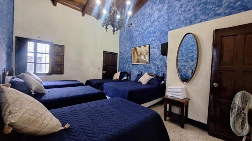 a blue room with four beds and a mirror at Hotel Posada San Miguel in Antigua Guatemala
