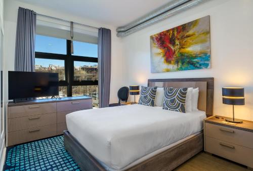 - une chambre avec un grand lit et une télévision dans l'établissement Dharma Home Suites Hoboken, à Hoboken