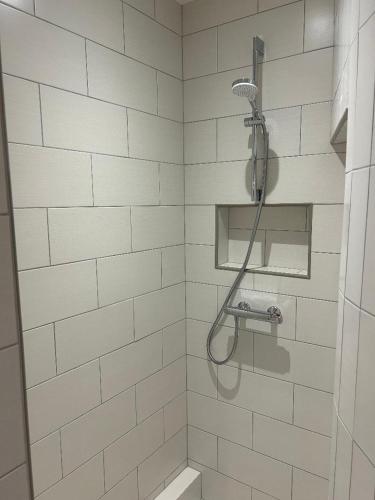 a white tiled shower with a shower head in a bathroom at Tichy in Paris