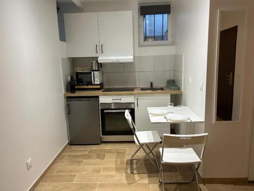 une cuisine avec des armoires blanches et une table et des chaises dans l'établissement Tichy, à Paris