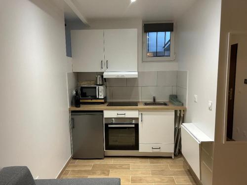 a small kitchen with white cabinets and a microwave at Tichy in Paris