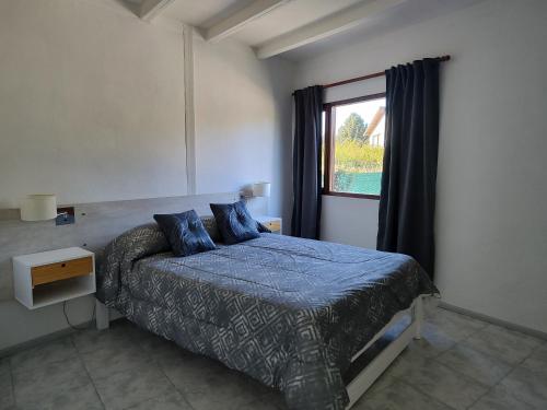 a bedroom with a bed with a blue comforter and a window at Sol de montaña, Bariloche. in San Carlos de Bariloche