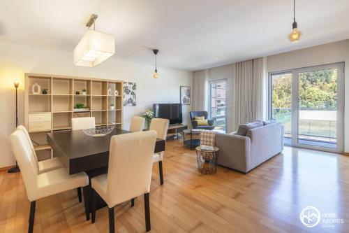 a dining room and living room with a table and chairs at Home Azores - Pico do Salomão Poolside Retreat in Ponta Delgada