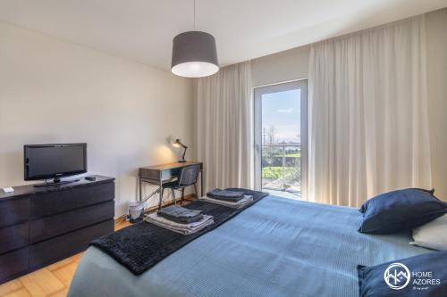a bedroom with a blue bed and a television at Home Azores - Pico do Salomão Poolside Retreat in Ponta Delgada
