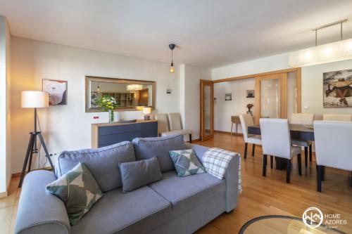 a living room and dining room with a blue couch at Home Azores - Pico do Salomão Poolside Retreat in Ponta Delgada