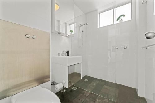 a white bathroom with a toilet and a shower at Modern Potts Point Studio in Sydney