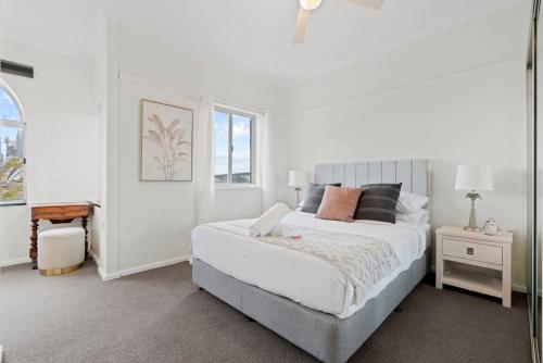 a white bedroom with a bed and a window at Lovely Apartment with Spectacular Views in Sydney