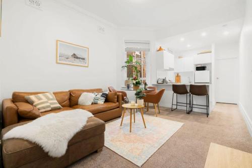 uma sala de estar com um sofá castanho e uma cozinha em Spacious Boutique Apartment in Beautiful Art Deco Block em Sydney