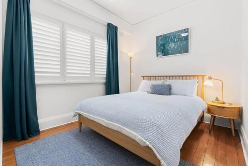シドニーにあるCoogee Rivieraのベッドルーム1室(ベッド1台、青いカーテン付きの窓付)