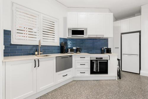 シドニーにあるCoogee Rivieraの白いキャビネットと青いタイルのキッチン