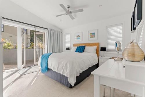a white bedroom with a bed and a desk at Bright Home in Trendy Newtown close to the Park in Sydney