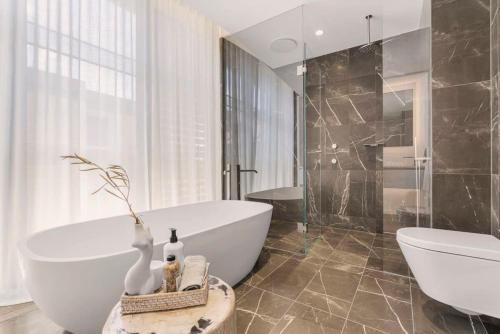 ein Badezimmer mit einer weißen Badewanne und einem Waschbecken in der Unterkunft Terrace Boutique in the Heart of The Rocks in Sydney