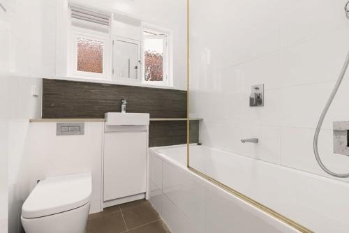 Baño blanco con aseo y lavamanos en Classic Art Deco, en Sídney