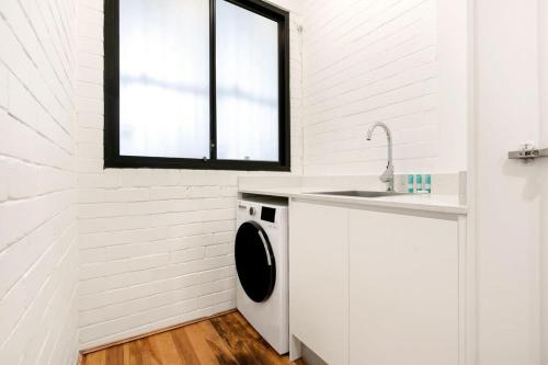 a white laundry room with a sink and a washing machine at Comfy Darlinghurst Retreat in Sydney