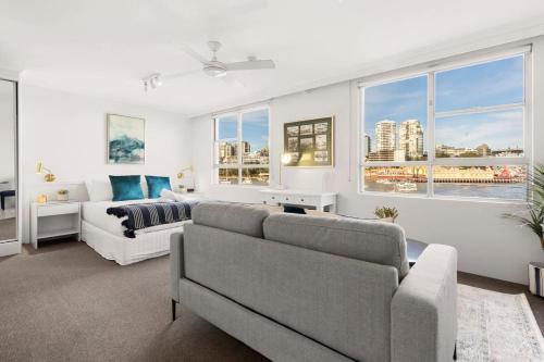 a living room with a couch and a bed and windows at Harbourside #15 in Sydney