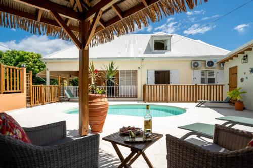 um pátio com uma mesa e cadeiras e uma piscina em Villa Ladouchka em Goyave