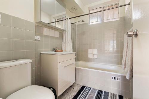 a bathroom with a toilet and a tub and a sink at Sunny Spot Potts Point in Sydney