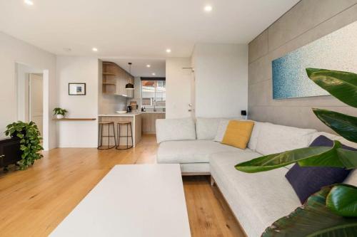 a living room with a white couch and a table at Coogee Beach Cosy Home in Sydney