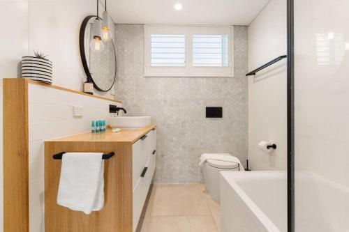 La salle de bains est pourvue d'un lavabo, d'une baignoire et de toilettes. dans l'établissement A Light Filled Contemporary Design Apartment, à Sydney
