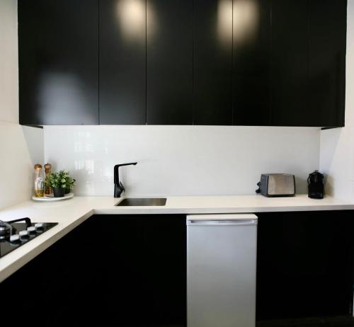 a kitchen with black cabinets and a sink at Lux & Quiet Apartment in, Potts Point in Sydney