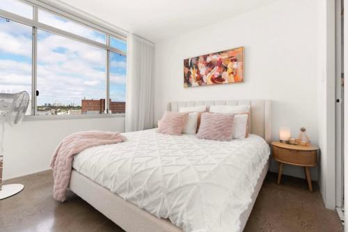 a white bedroom with a bed and a window at Best of city-suburbs living in trendy Darlinghurst in Sydney