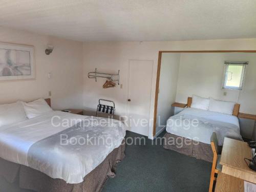 um quarto com 2 camas, uma mesa e uma janela em Campbell River Lodge em Campbell River