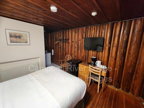 una camera da letto con pareti in legno, un letto e una TV di Campbell River Lodge a Campbell River