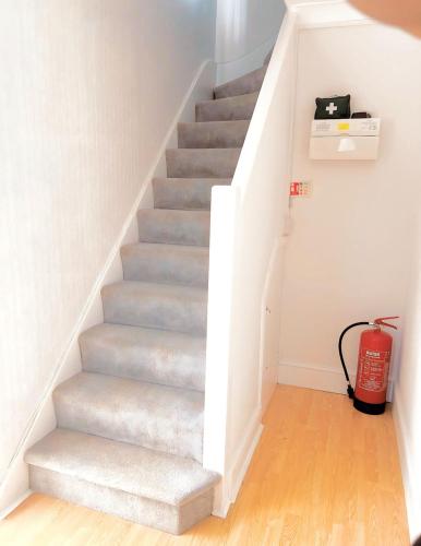 a staircase in a house with a red fire extinguisher at Hickory Haven in Borehamwood