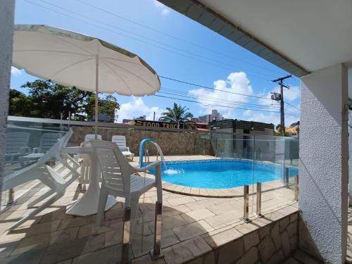 een patio met een zwembad, stoelen en een parasol bij Apartamentos na Praia de Camboinha/ Cabedelo/João Pessoa in Cabedelo