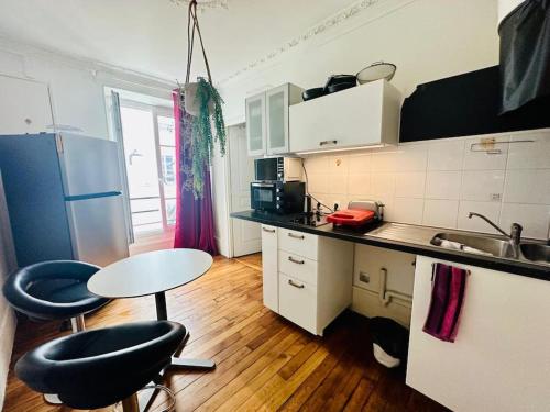 - une cuisine avec deux tabourets, une table et un évier dans l'établissement Studio animé et nifty à Paris/Denfert Rochereau, à Paris