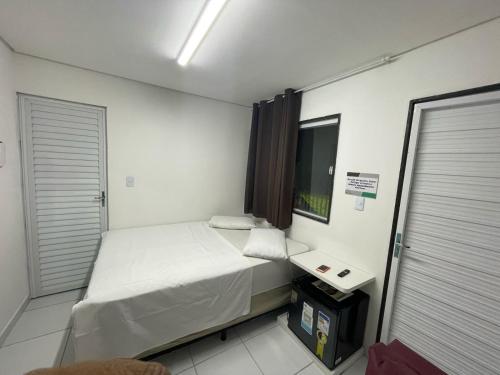 um pequeno quarto com uma cama e uma pequena mesa em Flat Rainha da Serra em Bezerros