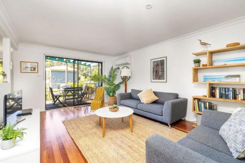 a living room with two couches and a table at Sandpiper, Hyams Beach in Hyams Beach