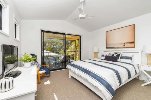 a bedroom with a bed and a tv and a window at Sandpiper, Hyams Beach in Hyams Beach