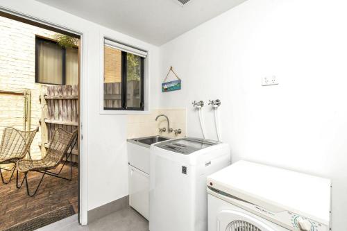 a small kitchen with a sink and a washing machine at Sandpiper, Hyams Beach in Hyams Beach