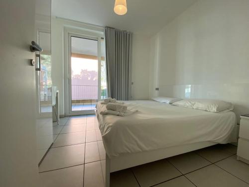 Maccagno InferioreにあるModern 3 bedroom apartment on Lake Maggioreのベッドルーム(白いベッド1台、大きな窓付)
