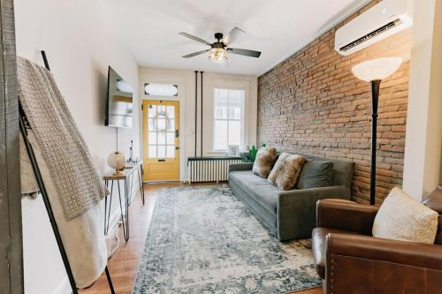 a living room with a couch and a brick wall at Comfy renovated townhome - heart of Downtown Lancaster in Lancaster