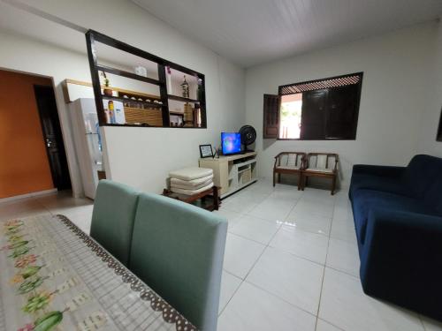 un salon avec un canapé bleu et une télévision dans l'établissement 1Mar doce lar Japaratinga-AL, à Japaratinga