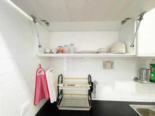 a kitchen with a sink and a shelf with dishes at Roxy Sematan Beach Townhouse Deluxe , 1 & 2 in Sematan