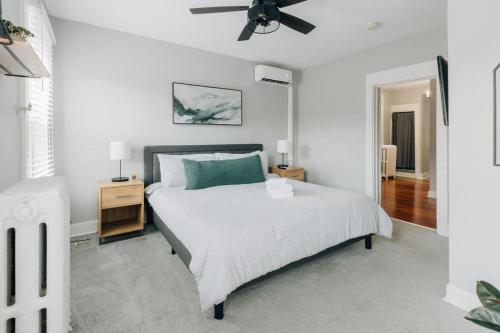 a white bedroom with a bed and a ceiling fan at Comfy renovated townhome - heart of Downtown Lancaster in Lancaster