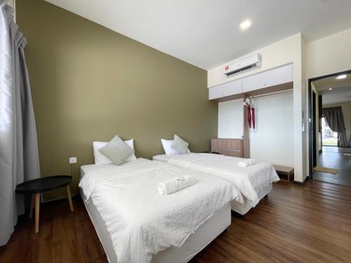 two beds with white sheets in a room at Roxy Sematan Beach Townhouse Deluxe , 1 & 2 in Sematan