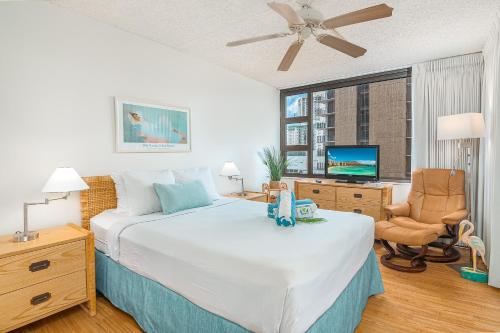 ホノルルにあるWaikiki Banyan Cozy Condo Suite - Ocean View with Free Parking!のベッドとテレビ付きの机のある寝室