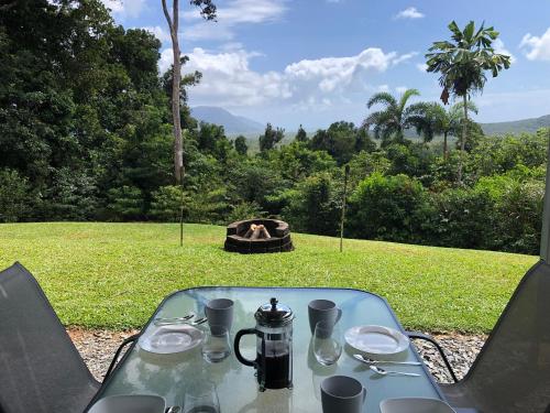 a table with a tea kettle and a fire in a field at Daintree - House with a view in Cow Bay