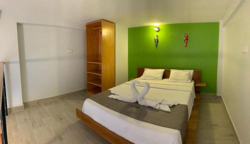 1 dormitorio con 1 cama con pared verde en La Quinta Loft Apartments, en Iquitos