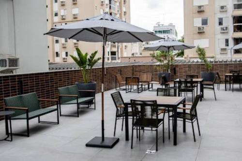 a patio with tables and chairs and an umbrella at Apartamento Studio Hub Smart in Criciúma