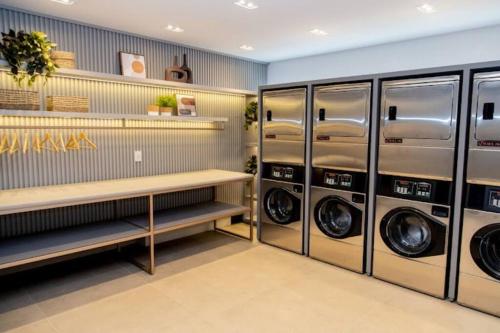 - une buanderie avec 3 lave-linge et sèche-linge dans l'établissement Apartamento Studio Hub Smart, à Criciúma