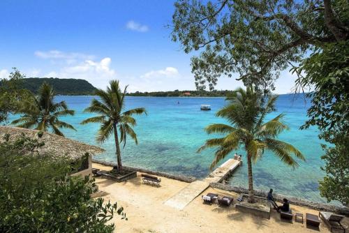 a beach with palm trees and a body of water at Iririki Island Resort & Spa in Port Vila