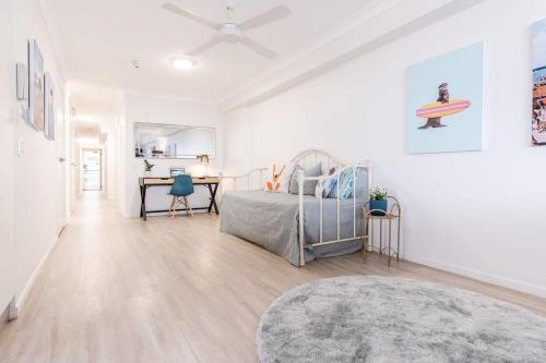 a white room with a bed and a table at Kings Beach Coast and Glasshouse Views in Caloundra