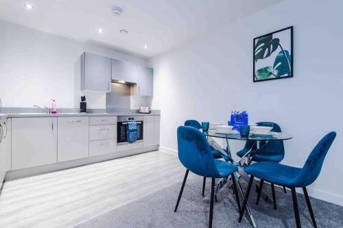 uma cozinha com uma mesa de vidro e cadeiras azuis em Luxury 2BR Apartment in Central *FREE PARKING* em Manchester