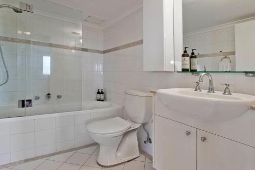 a white bathroom with a toilet and a sink at Expansive Views From Sydney 1 Bedroom Apartment in Sydney